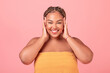 © Prostock-studio - Portrait of excited black body positive woman touching face and enjoying her smooth skin, pink studio background