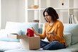 © Prostock-studio - Wrong Parcel. Confused arab woman looking at open cardboard box at home