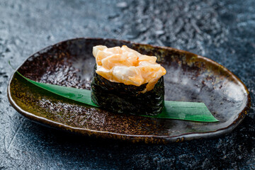 Sticker - Gunkan with a scallop sharp, spicy sauce on dark stone table