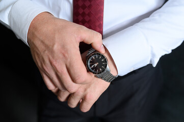 Wall Mural - A man straightens a watch strap, close-up. Young modern businessman. Business style clothing concept, wedding