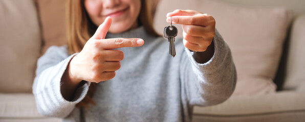 Wall Mural - Closeup image of of a woman holding and pointing finger at the keys for real estate concept