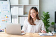 © amnaj - Attractive Asian businesswoman with laptop in office With a bright smile and looking at the camera.