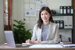 © amnaj - Attractive Asian businesswoman with laptop in office With a bright smile and looking at the camera.