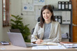 © amnaj - Attractive Asian businesswoman with laptop in office With a bright smile and looking at the camera.