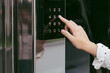 © Maria - Woman's hand using an intercom at entrance to building. Using an electronic lock