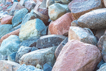 Wall Mural - Close-up of a pile of large granite stones with a fine texture. Background with a protective embankment of pebbles on the beach.