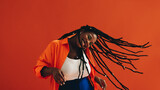 Young, fashionable black woman celebrates and enjoys herself with a hair flip, dancing and smiling in a vibrant studio setting