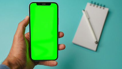 Mobile phone with empty blank green screen flat lay, Smartphone isolated on blue colour background