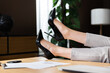 Time for rest. Close up shot woman's legs in high heels shoes on working place desk near papers laptop. Relax time in office home.