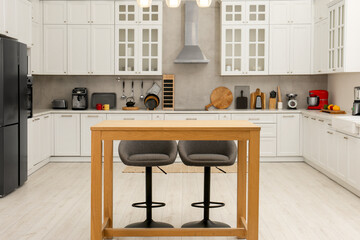 Wall Mural - Stylish modern furniture and wooden table with bar chairs in kitchen. Interior design