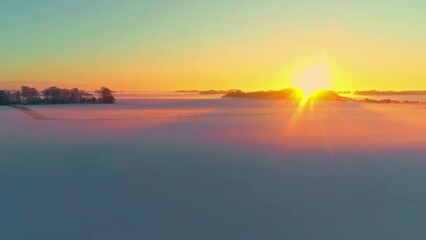 Wall Mural - The sun sets on the horizon and glows on the snowy fields of a winter landscape - aerial view