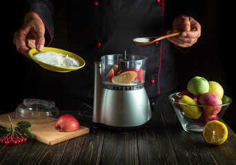 Professional chef prepares fresh apple juice in an electric blender. The cook adds sugar to the mixer with a spoon. Menu idea for a hotel or restaurant. Copy space