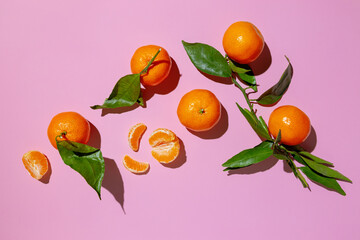 Wall Mural - Fresh tangerine with leaves on pink background.