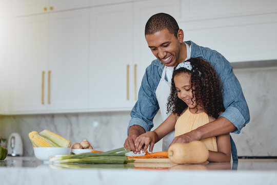Love, father and girl cooking food with healthy vegetables for lunch or dinner meal as a happy family at home. Nutrition, smile or dad teaching or helping a young child cut carrots on kitchen counter