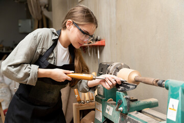 A female carpenter is working at a furniture factory with modern equipment and machinery.