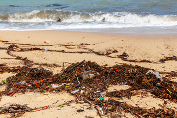 Garbage on sea sand beach, unsorted rubbish, plastic bags, glass bottle, metal can, trash, refuse pile, litter, dirty ocean water, environmental pollution, ecological problem concept, waste management