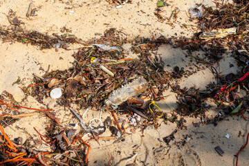 Garbage on sea sand beach, unsorted rubbish, plastic bags, glass bottle, metal can, trash, refuse pile, litter, dirty ocean water, environmental pollution, ecological problem concept, waste management