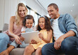 © Delcio F/peopleimages.com - Love, sofa and family with kids, tablet or social media for streaming, interracial or laugh together. Digital, father or mother with female children, device or watch funny videos and happy parents