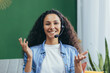 © Liubomir - Joyful hispanic woman with video call headset at home smiling and looking at camera, woman studying and working online remotely sitting on couch at home.