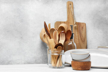 Different kitchenware and dishware on white wooden table against textured wall. Space for text