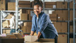 © Gorodenkoff - Portrait of a Happy African Small Business Owner Working on Laptop in Warehouse, Preparing Parcels for Delivery. Female Smile and Pose for Camera in Storeroom with Cardboard Boxes.