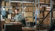 © Gorodenkoff - Multicultural Team of Warehouse Employees at Work in Retail Shop's Storeroom. Small Business Owners and Inventory Managers Working on Laptop, Packing Parcels for Delivery.