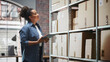 © Gorodenkoff - Portrait of a Manager Checking Inventory, Writing in Tablet Computer. Black Woman Working in a Warehouse Storeroom with Rows of Shelves Full of Parcels, Packages with Orders Ready for Shipment.