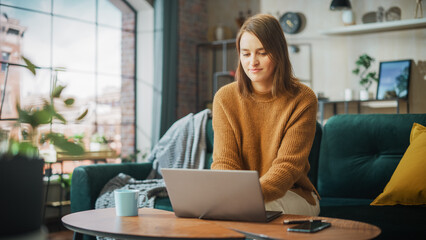 Poster - Portrait of Smiling Young Woman Working from Home on Laptop Computer in Sunny Cozy Apartment. Successful Creative Girl Entrepreneur Does Remote for e-Business Project, Online Shopping