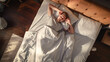 © Gorodenkoff - Top View Home: Handsome Young Man Sleeps in His Bed, Sun Shines on Him, He Opens Eyes and Greets New Sunny Day at Home. Joyful Waking Up of a Guy who is Ready for Productive Day. Top Down Above Shot