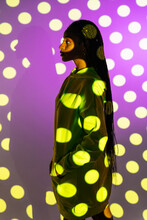 Black Female Model Standing Against Glowing Polka Dot Projector