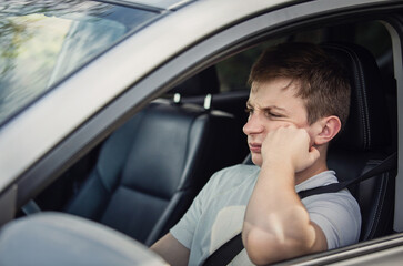 Upset and dissatisfied driver looking sullenly at the traffic jam ahead his car. Fatigue guy stuck at the rush hour