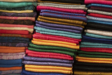 Close-up Of Three Piles Of Folded Silk Scarves In A Variety Of Colours; Bangkok, Thailand