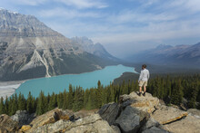 A Man Stands On A Rock Ridge Overlooking The Stunning Turquoise Water Of Peyto Lake In Banff National Park; Alberta, Canada