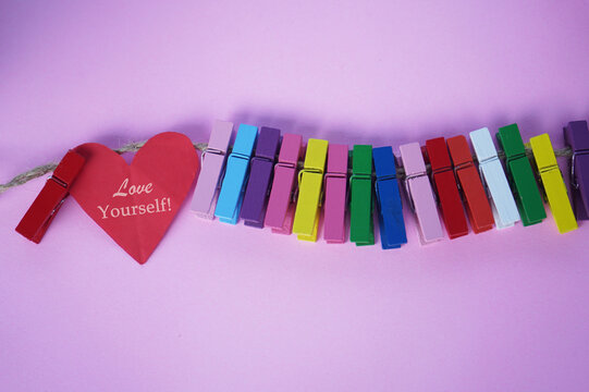 Wall Mural -  - Self love and care concept with inspirational motivational text on red heart - Love Yourself. On purple background of colorful wooden clips on rope.