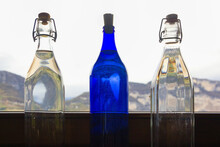 Three Bottles By The Window Against The Backdrop Of The Mountains
