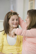 © Designpics - Teenage girl putting on a necklace on her sister, one with birth defect