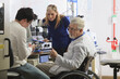 © Designpics - Professor with muscular dystrophy working with engineering students setting up adjustable stage at chemical analysis instrument in a laboratory
