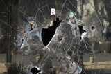 Fototapeta  - Broken glass of a street building. vandals smashed a shop window. Hooligans are breaking front windows. Law enforcement in the city