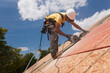 © Designpics - Hispanic carpenter using a circular saw on a roof sheathing at a house under construction