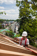 © Designpics - Hispanic carpenter hammering on roof window opening at a house under construction