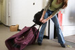 © Designpics - Young woman pulling a huge traveling bag.