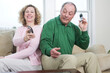 © Designpics - View of a mature couple sitting back to back with mobile phones and cordless.