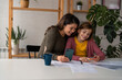 © Dorde - Mother and daughter making an online reservation...Joyful mom and her little excited daughter sitting at home and making an online reservation for a future trip.