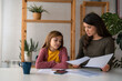 © Dorde - A serious mother and a pensive daughter going through the homework together. Stressed mother and daughter frustrated over failure homework. Education at home concept.
