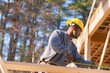 © Designpics - Carpenter measuring rafter length for house construction