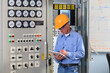© Designpics - Electrical engineer inspecting power plant controls in central operations room of power plant