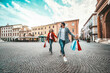 © Davide Angelini - Happy beautiful young couple holding shopping bags walking on city street - Two loving tourists having fun on weekend vacation - Holidays and shopping concept