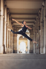 Young man dancing classic ballet in the streets of Barcelona with a beautiful background and light