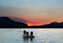 Young Family Watching A Sunset While Swimming In A Lake, Ruby Lake On The Sunshine Coast Of BC, Canada; British Columbia, Canada
