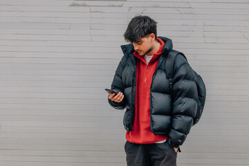 Wall Mural - boy with mobile phone on the street in warm clothes